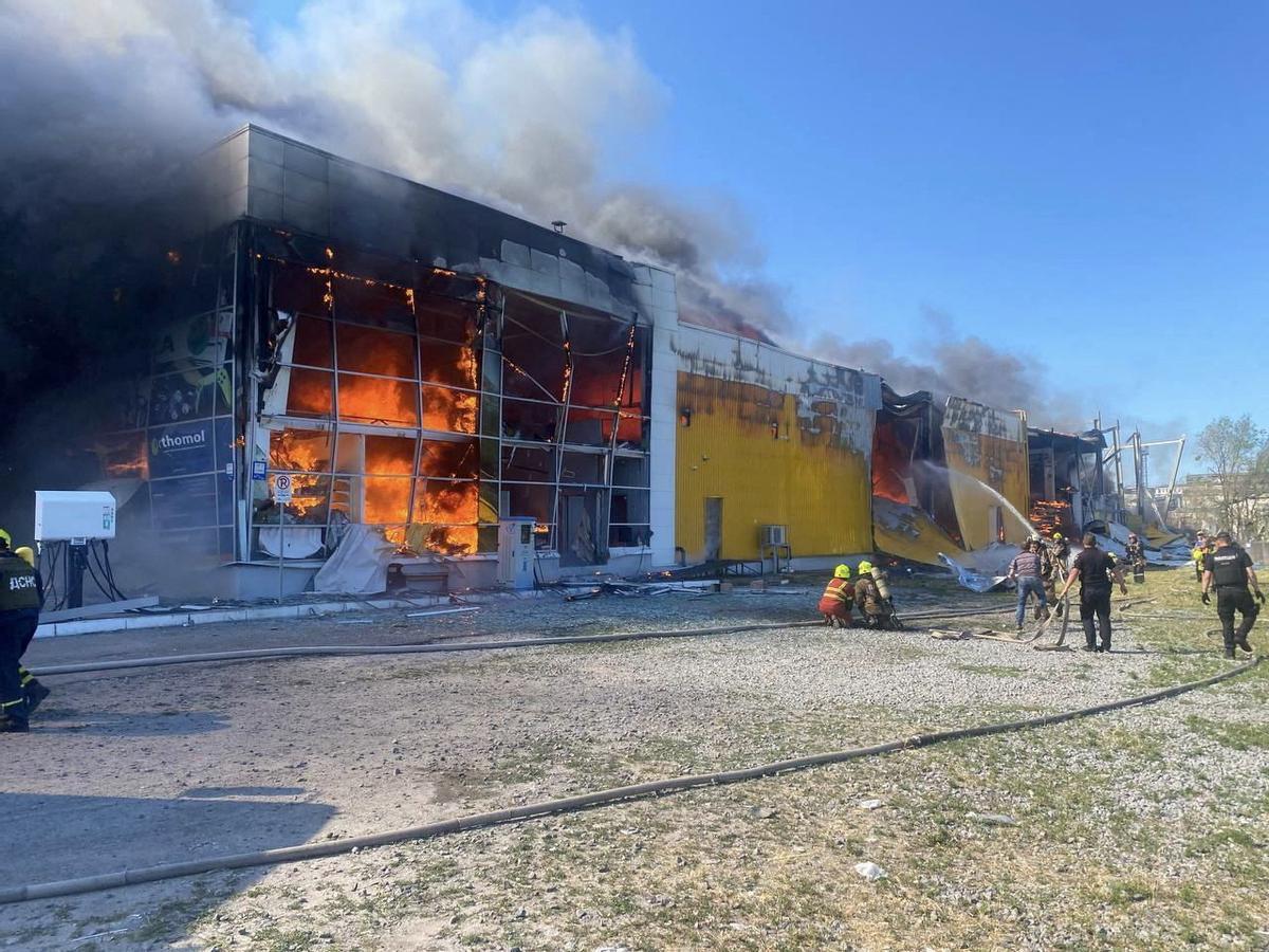 Bomberos tratan de apagar el incendio en el centro comercial atacado en Kremenchuk (Ucrania).