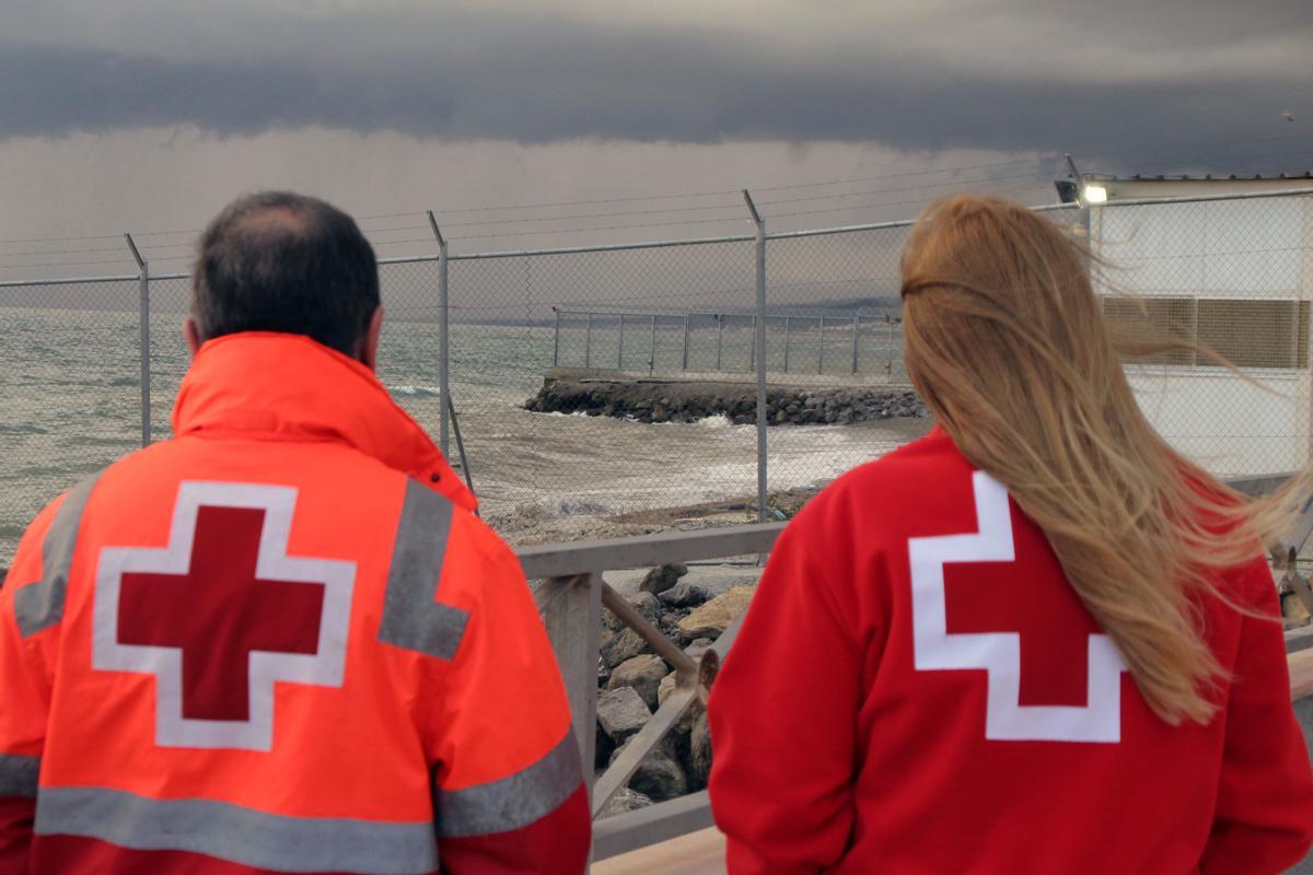 Imagen de archivo de dos trabajadores de Cruz Roja observando en Ceuta el espigón fronterizo con Marruecos. EFE/Reduan Dris
