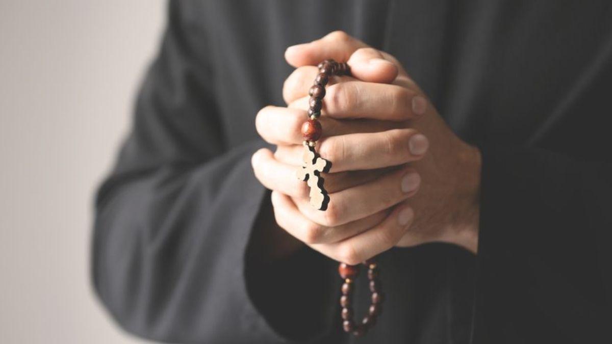 Un religioso orando con un rosario en las manos.