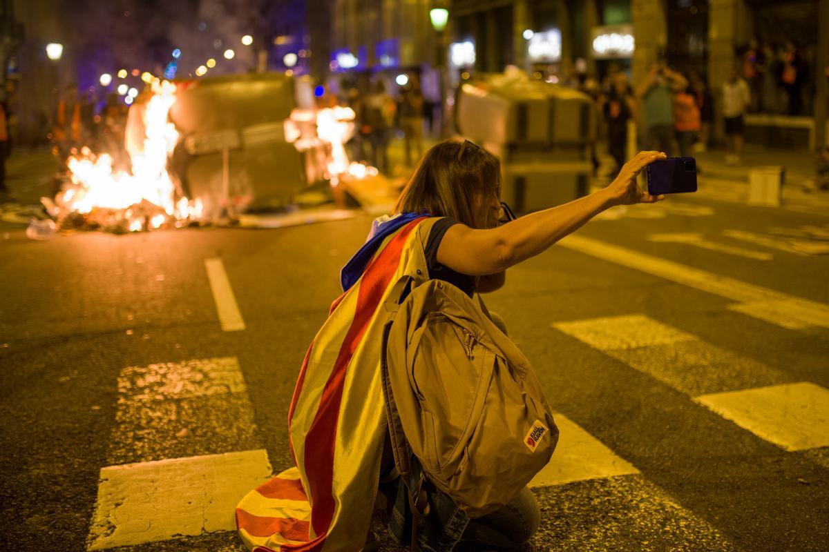 Una manifestante independentista se hace un selfie con un contenedor ardiendo durante una manifestación por el referéndum del 1-O en Cataluña.