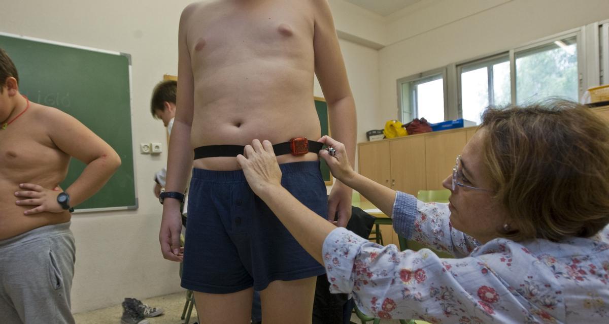 Medición del perímetro de cintura de los alumnos en un colegio por parte de la enfermera.