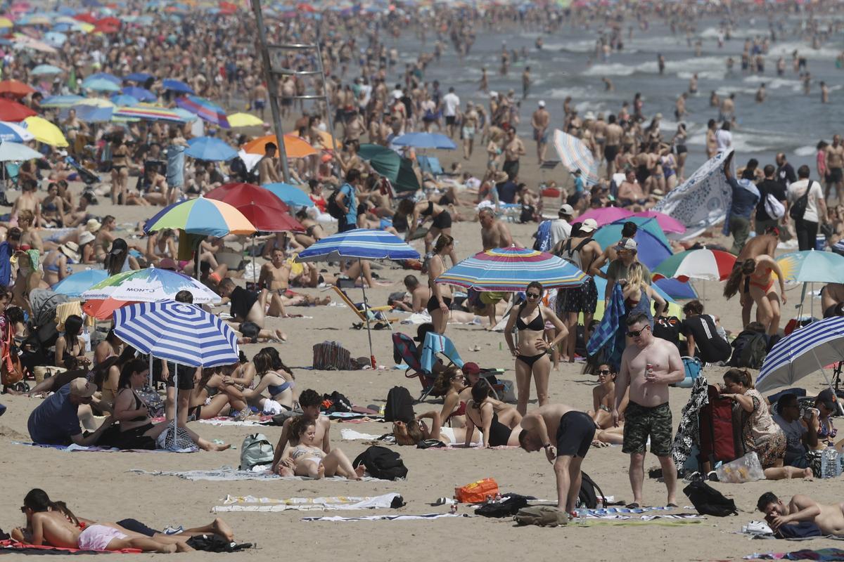 Cientos de personas disfrutan del buen tiempo en la playa de la Malvarosa de Valencia.