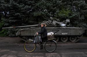 Una mujer en bicicleta junto a un tanque. EPC