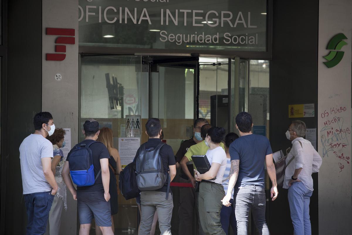 Un grupo de personas hace cola ante una oficina de la Seguridad Social