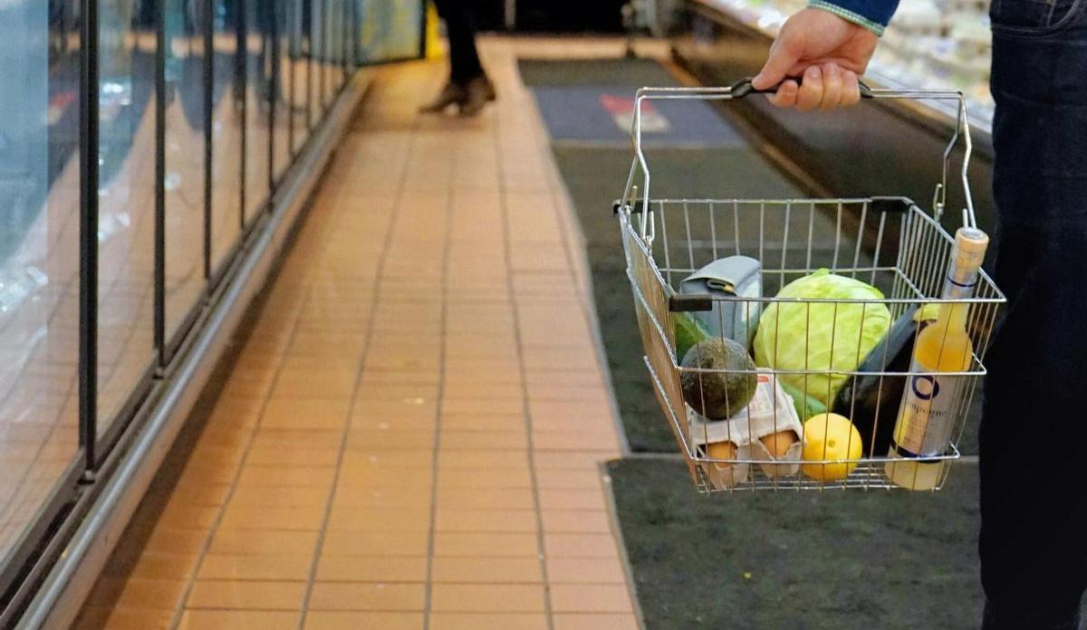 Gente comprando en un supermercado con la cesta de la compra