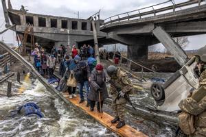 Civiles cruzan un puente hundido mientras huyen del asedio de Irpin (Ucrania).
