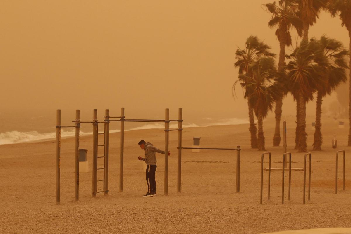 Un joven hace deporte en una playa de Roquetas (Almería), bajo una intensa calima debido al polvo procedente del desierto del Sáhara. EFE/Carlos Barba