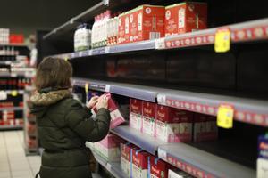 Una mujer coge un brick de leche de la estantería de leche que le faltan algunos productos, en un supermercado Carrefour, a 18 de marzo de 2022, en Madrid.