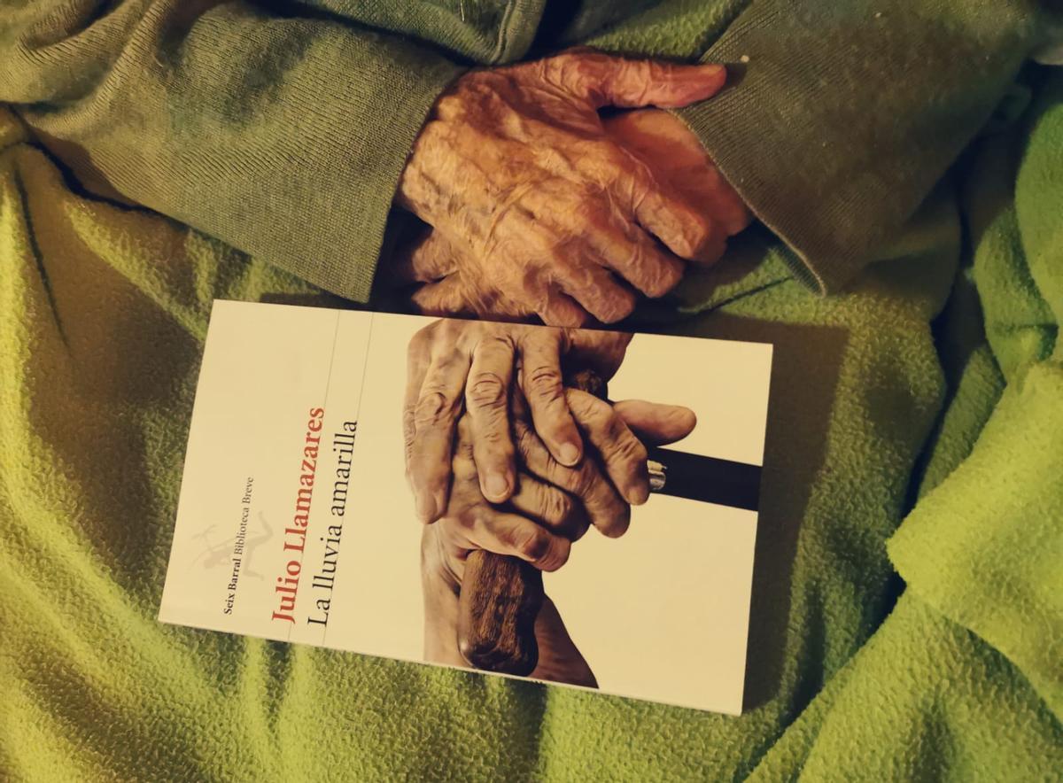 Las manos de María de Ruidelamas sosteniendo el libro ’La lluvia amarilla’, del que inspiró la última frase.