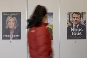 Un votante pasa frente a los carteles electorales de Marine Le Pen (izquierda) y Emmanuel Macron (derecha) para las elecciones presidenciales francesas en el colegio electoral Palexpo en Ginebra, Suiza.