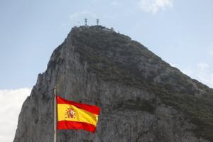 La bandera de España ondea en la Verja, el límite fronterizo con Gibraltar, con el Peñón al fondo. 