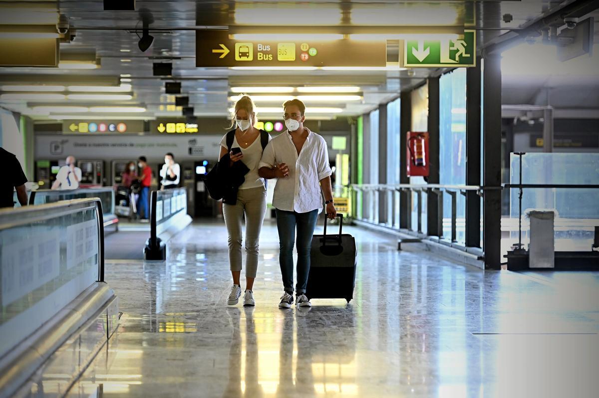 Una pareja camina por los pasillos del Aeropuerto de Barajas con una maleta.