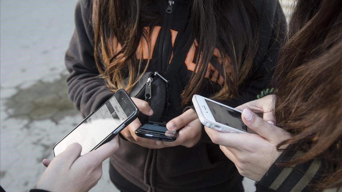 Unas adolescentes usan sus teléfonos móviles en Barcelona.