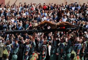 Legionarios del Tercio Gran Capitán, con sede en Melilla, alzan la figura del Cristo de la Buena Muerte y Ánimas mientras lo trasladan a la casa hermandad de la Cofradía de Mena este Jueves Santo en Málaga. 