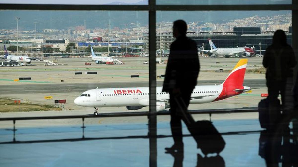 Pasajeros en un aeropuerto frente a un avión de Iberia.