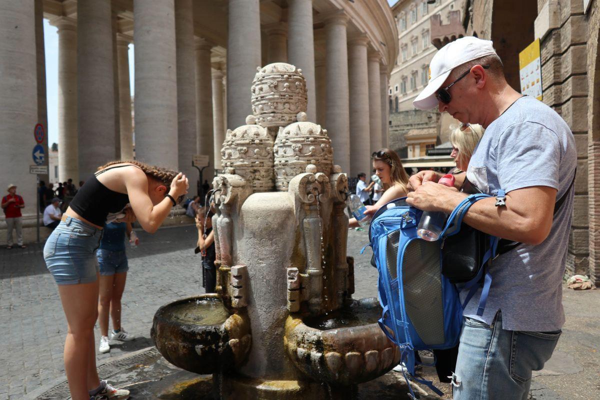 Varias personas se refrescan en una fuente en el Vaticano.