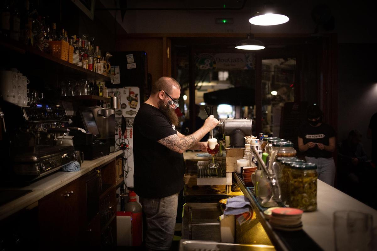 Un camarero sirve una cerveza en el interior de un bar.