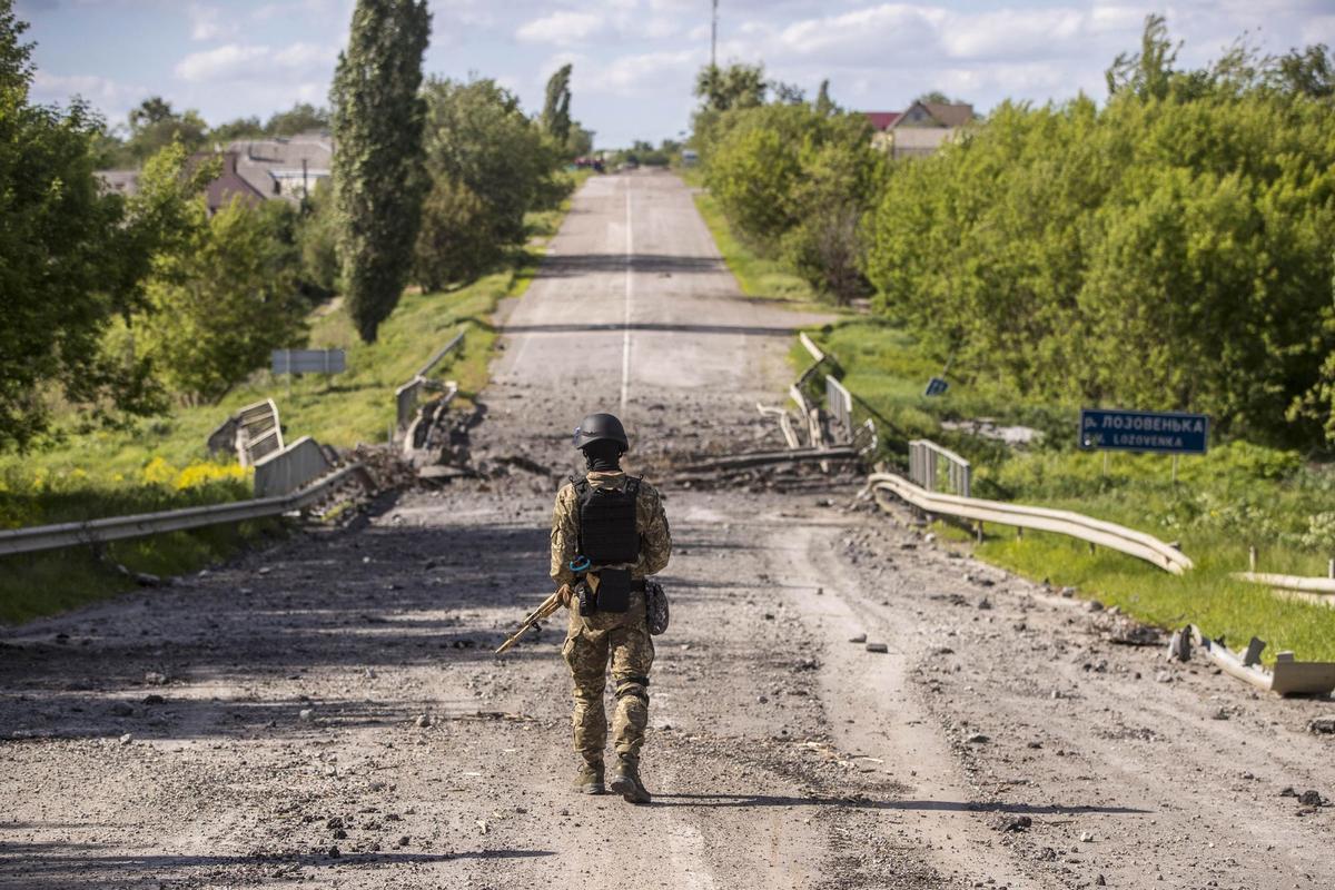 GRAF2765. TSYRKUNY (UCRANIA), 30/05/2022.- Foto del pasado 27 de mayo de 2022, en el que se ve a un soldado patrullando entre los restos de un puente cerca del campo de batalla. Las explosiones de proyectiles son de lo poco que se escucha en aldeas próximas a la línea de combate en Járkov, en el este de Ucrania, donde el tiempo parece haberse detenido y queda el recuerdo de lo que vivieron los vecinos cuando llegaron las tropas rusas. Olexandr Yena, que vive en uno de estos pequeños pueblos, Tsyrkuny, cuenta a Efe que junto a otros dos vecinos estaba en la calle un día de marzo cuando vieron llegar a militares rusos. EFE/Esteban Biba