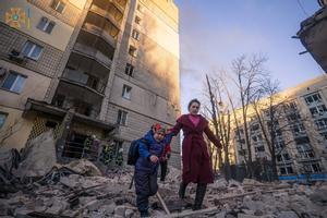 Una mujer y un niño se alejan de un edificio dañado por los bombardeos en Kiev.