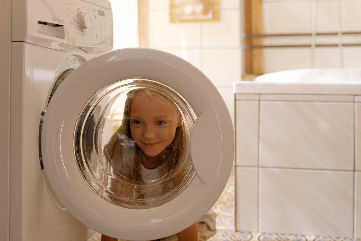 Una niña frente a una lavadora