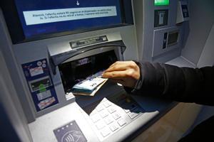 Un ciudadano retira dinero de un cajero automático