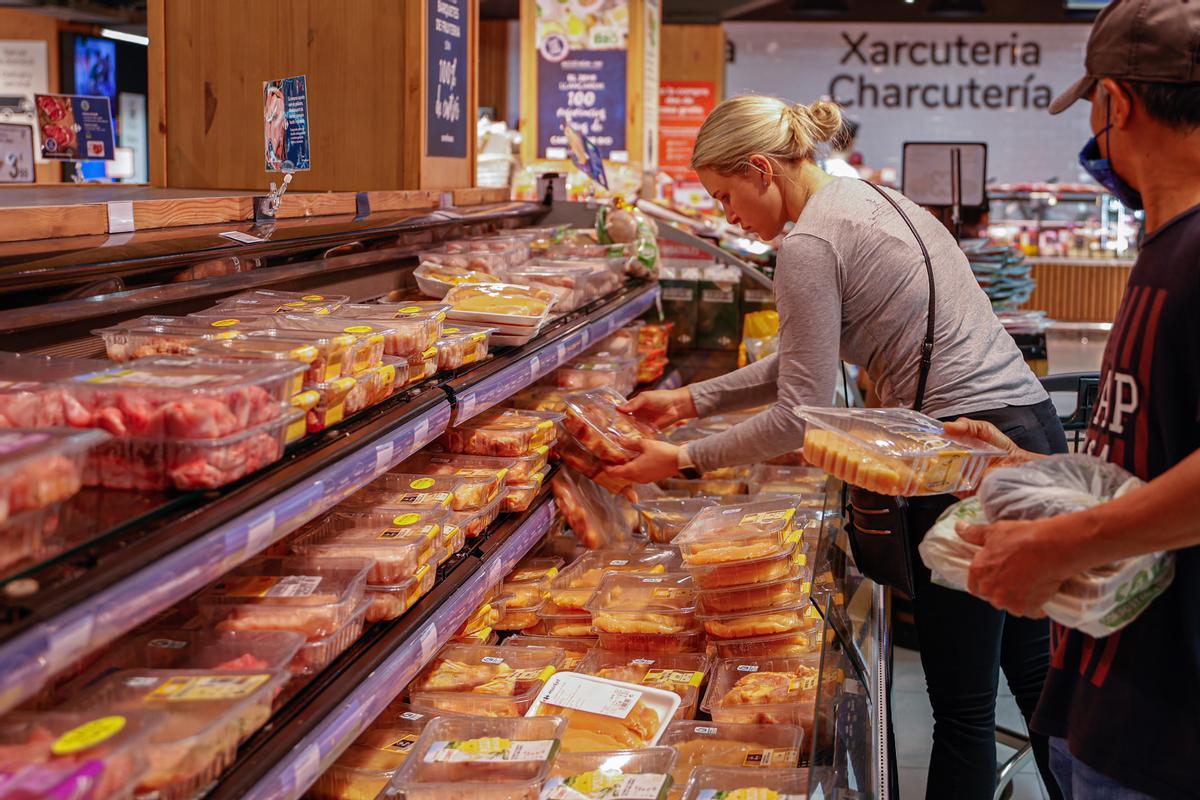 Varias personas realizan la compra en un supermercado.